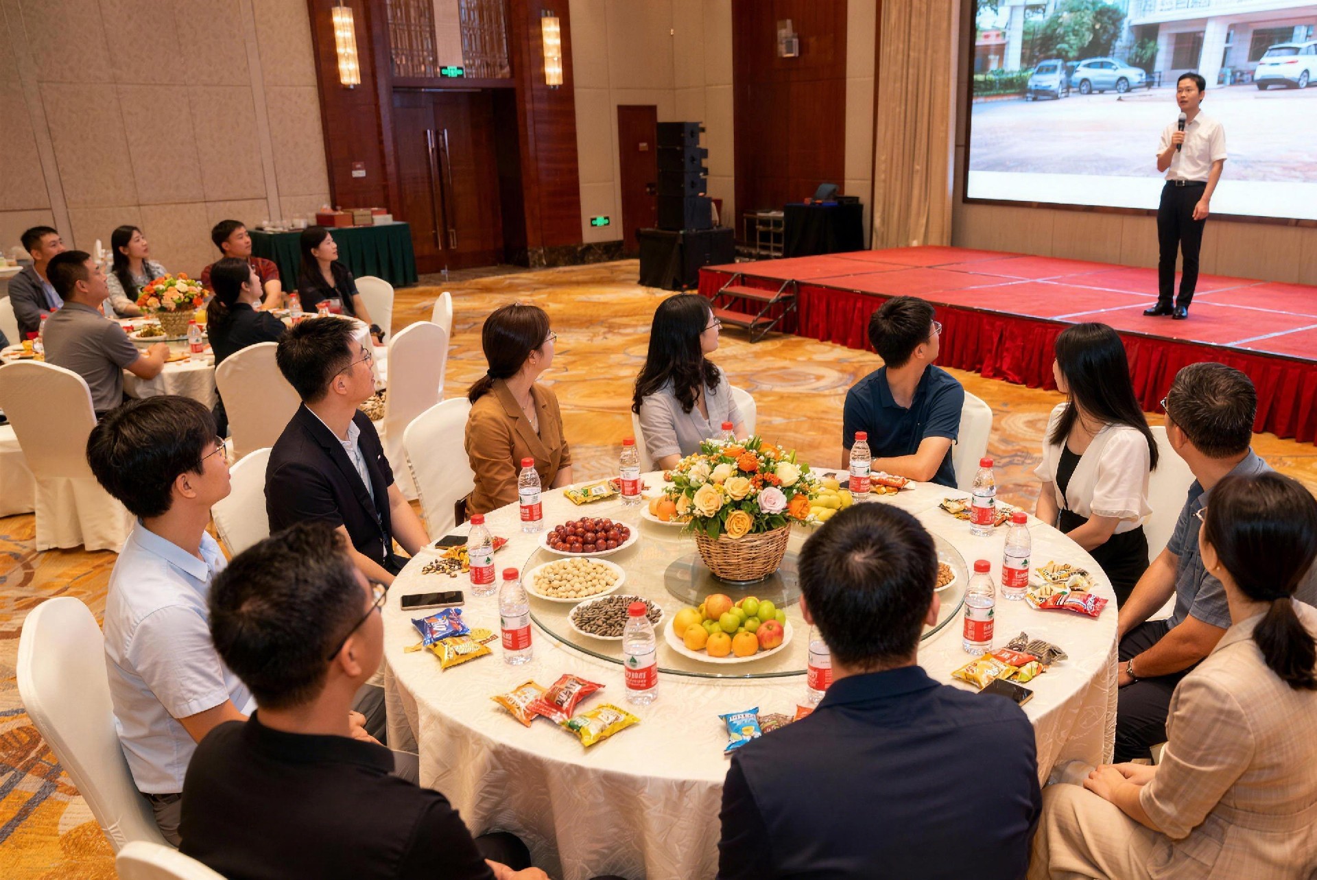 jimeng-2025-11-30-2014-13 个人围坐在一个酒店桌子边，男女都有，全景，桌子上有个装饰花篮，每个人的桌上..jpg